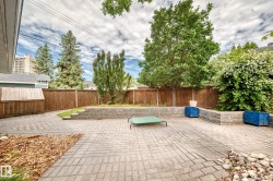 Paved patio area featuring brick-patterned pavers and a wood privacy fence - 