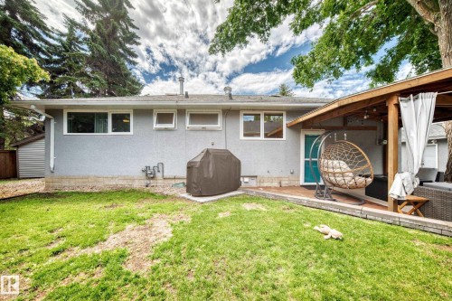 Expansive rear yard featuring green space, a wooden deck, and a covered patio area with exposed wood beams - 16406 87A Avenue Nw, Edmonton, AB - Outdoor