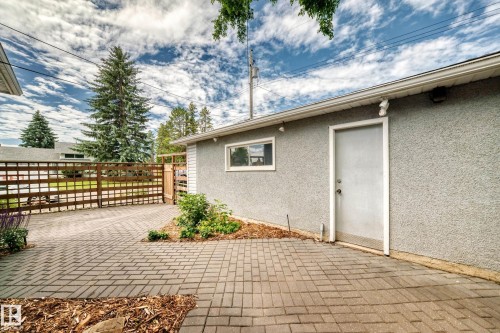 Stucco exterior with a side entry door, white window trim, and a paved brick driveway - 16406 87A Avenue Nw, Edmonton, AB - Outdoor