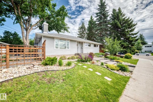Siding exterior with a prominent window, a gray shingled roof, a gray chimney, and a landscaped front yard with stepping stones - 16406 87A Avenue Nw, Edmonton, AB - Outdoor