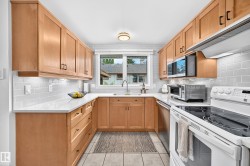 U-shaped kitchen featuring light wood cabinetry, white countertops, and a subway tile backsplash - 