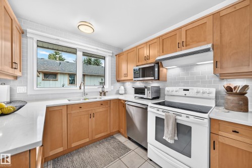 Kitchen featuring light wood-finish cabinetry, white countertops, tile flooring, subway tile backsplash, and a stainless steel dishwasher - 16406 87A Avenue Nw, Edmonton, AB - Indoor Photo Showing Kitchen With Double Sink