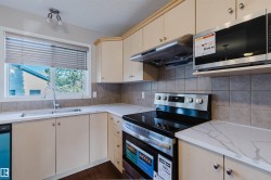 Contemporary kitchen featuring a stainless steel electric range, over-range microwave, and a double basin sink with a gooseneck faucet - 