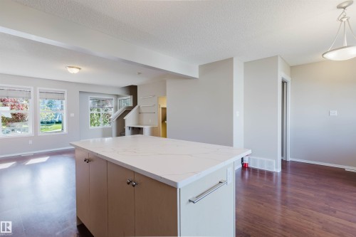 Kitchen island featuring a light-toned countertop, wood-finish flooring, recessed lighting, and multiple windows - 5887 Sutter Place Nw, Edmonton, AB - Indoor Photo Showing Kitchen