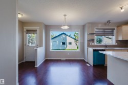 Open concept living space featuring wood-finish flooring, a large picture window, and a built-in kitchen island with a light-toned countertop - 