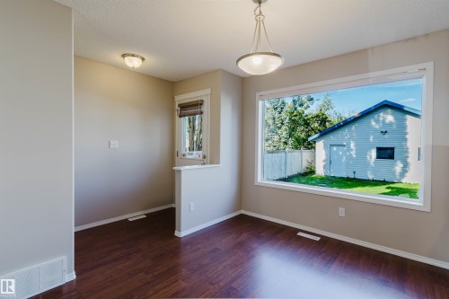 Wood-finish flooring, neutral wall tones, and a large window - 5887 Sutter Place Nw, Edmonton, AB - Indoor Photo Showing Other Room