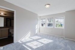 Light gray wall paint, gray carpet, three windows, flush mount ceiling light fixture, doorway to a bathroom - 
