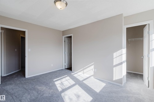 Neutral-toned walls, gray carpeting, a flush-mount ceiling light fixture, and white interior doors - 5887 Sutter Place Nw, Edmonton, AB - Indoor Photo Showing Other Room