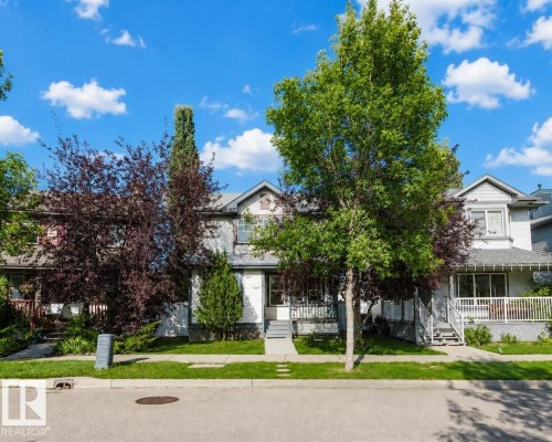 Multi-story exterior with a covered porch, white railing, and exterior staircase - 5887 Sutter Place Nw, Edmonton, AB - Outdoor