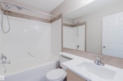 Bathroom featuring a combination shower and tub, tile surround, integrated vanity sink, and a large wall-mounted mirror - 