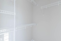 Built-in wire shelving system, multiple hanging rods, and light-toned wall paint - 
