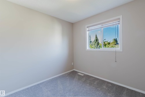 Soft gray wall finish, gray carpet, white window trim, and a window with a roller shade - 5887 Sutter Place Nw, Edmonton, AB - Indoor Photo Showing Other Room