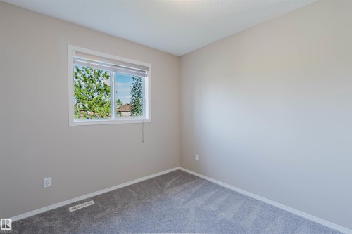 Neutral wall paint, gray carpet, and a window with white trim - 5887 Sutter Place Nw, Edmonton, AB - Indoor Photo Showing Other Room