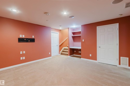 Recessed lighting, built-in shelving, integrated desk, wall-mounted television bracket, and carpeted flooring - 5887 Sutter Place Nw, Edmonton, AB - Indoor Photo Showing Other Room