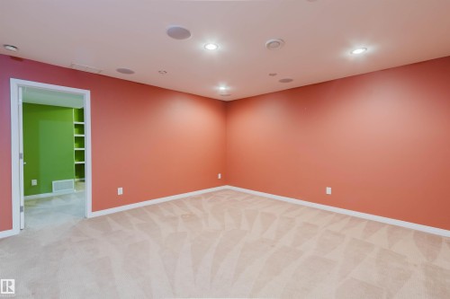 Recessed lighting, ceiling-mounted speakers, light-toned carpeting, and a built-in shelving unit - 5887 Sutter Place Nw, Edmonton, AB - Indoor Photo Showing Other Room