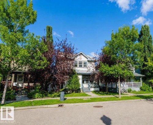 Traditional-style exterior with light siding, a gabled roofline, and multiple mature trees - 5887 Sutter Place Nw, Edmonton, AB - Outdoor