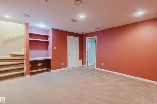 Recessed lighting, built-in shelving, white interior door, light-colored carpeting, and a glass-paneled interior door - 5887 Sutter Place Nw, Edmonton, AB - Indoor Photo Showing Other Room