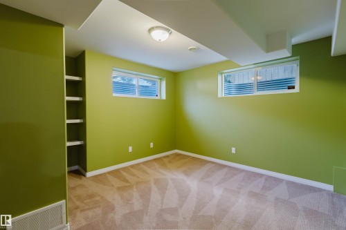 Room featuring built-in shelving, two windows with white trim, and a ceiling-mounted light fixture - 5887 Sutter Place Nw, Edmonton, AB - Indoor Photo Showing Other Room