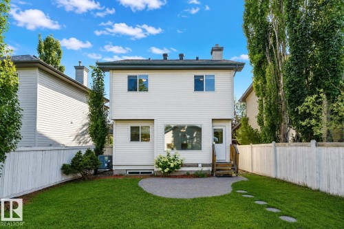 Expansive backyard featuring a manicured lawn, established privacy fencing, and a curved patio area with stepping stones - 5887 Sutter Place Nw, Edmonton, AB - Outdoor