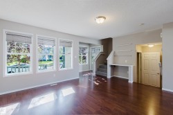 Hardwood-finish flooring throughout, multiple windows with blinds, built-in shelving, carpeted staircase, and an interior paneled door - 