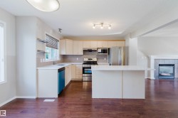 Kitchen featuring wood-finish flooring, stainless steel appliances, a center island with countertop seating, and a tile backsplash - 