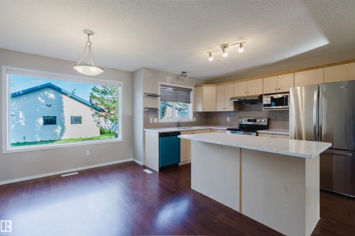 Hardwood-finish flooring, recessed lighting, track lighting, kitchen island with countertop, and stainless steel appliances - 5887 Sutter Place Nw, Edmonton, AB - Indoor Photo Showing Kitchen With Stainless Steel Kitchen