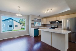 Hardwood-finish flooring, recessed lighting, track lighting, kitchen island with countertop, and stainless steel appliances - 