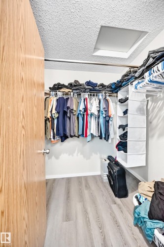 Spacious closet featuring wood-finish flooring, white walls, and built-in closet rods - #158 180 Bridgeport Bv, Leduc, AB - Indoor With Storage