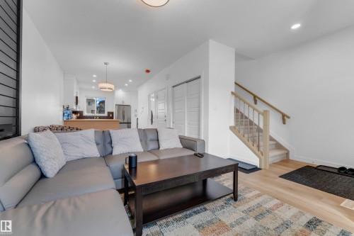Open-concept living area featuring light wood-finish flooring, a modern staircase with wood handrails, and recessed ceiling lighting - 3610 42 Avenue, Beaumont, AB - Indoor Photo Showing Living Room