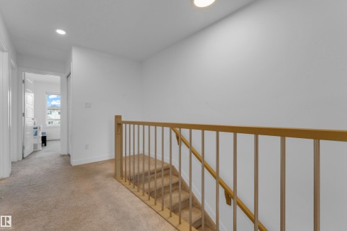 Carpeted hallway with recessed lighting and a carpeted staircase featuring a light wood railing - 3610 42 Avenue, Beaumont, AB - Indoor Photo Showing Other Room