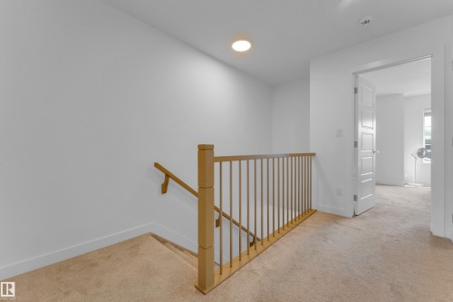 Carpeted hallway with a light wood-finish railing and a recessed ceiling light fixture - 3610 42 Avenue, Beaumont, AB - Indoor Photo Showing Other Room