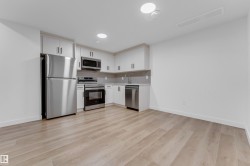 Contemporary kitchen featuring stainless steel appliances, light-toned cabinetry, and wood-finish flooring - 