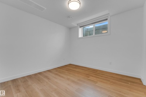 Recessed window with blinds, wood-finish flooring, flush mount ceiling light fixture, white painted walls, and white trim - 3610 42 Avenue, Beaumont, AB - Indoor Photo Showing Other Room