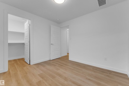 Wood-finish flooring, white walls, built-in closet shelving, and a flush mount ceiling light - 3610 42 Avenue, Beaumont, AB - Indoor Photo Showing Other Room