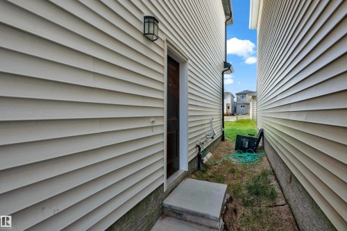 Cream-colored horizontal siding with a dark entry door and exterior light fixture - 3610 42 Avenue, Beaumont, AB - Outdoor
