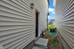 Cream-colored horizontal siding with a dark entry door and exterior light fixture - 