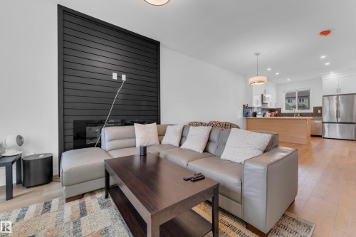 Living space with wood-finish flooring, a black slatted accent wall, and an integrated fireplace - 3610 42 Avenue, Beaumont, AB - Indoor Photo Showing Living Room