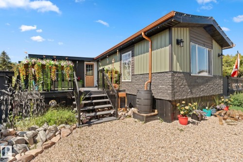 Exterior featuring a multi-level deck with black railing, exterior lighting fixtures, and a rain barrel collection system - 5024 45A Street, Barrhead, AB - Outdoor