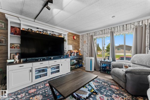 Built-in entertainment center with open shelving, integrated cabinetry, and wood-finish accent wall - 5024 45A Street, Barrhead, AB - Indoor Photo Showing Living Room