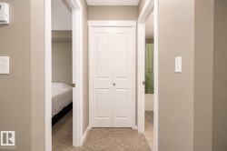 Carpeted hallway with painted walls, white bi-fold closet doors, and white trim - 
