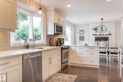 White cabinetry with stainless steel appliances, light-toned countertops, and a subway tile backsplash - 