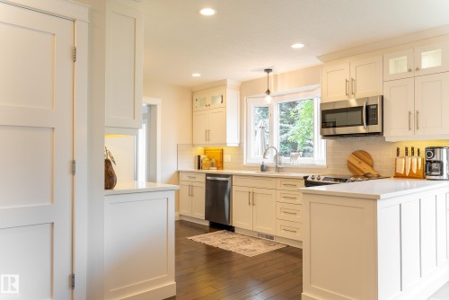 White shaker-style cabinetry, recessed lighting, stainless steel appliances, wood-finish flooring, and white countertops - 56 Highridge Way, Stony Plain, AB - Indoor Photo Showing Kitchen