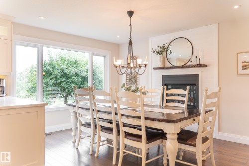 Built-in fireplace with a dark mantel, large multi-pane window, dark wood-finish flooring, and recessed lighting - 56 Highridge Way, Stony Plain, AB - Indoor Photo Showing Dining Room With Fireplace