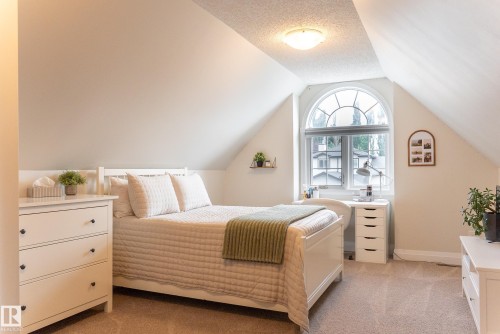 Arched window with decorative grille, sloped ceiling, recessed lighting, wall-to-wall carpeting, and neutral paint palette - 56 Highridge Way, Stony Plain, AB - Indoor Photo Showing Bedroom