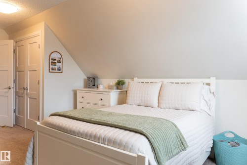 Sloped ceiling room featuring white panel doors, built-in closet, and light-colored carpeting - 56 Highridge Way, Stony Plain, AB - Indoor Photo Showing Bedroom
