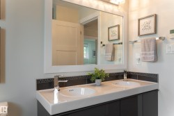 Dual vanity with integrated sinks, chrome fixtures, dark wood-finish cabinetry, and a full-width mirror - 