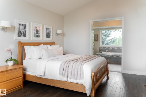 Hardwood flooring, light wall sconces, and a dedicated bathroom entrance with a window - 56 Highridge Way, Stony Plain, AB - Indoor Photo Showing Bedroom