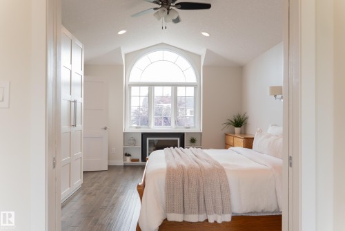Vaulted ceiling with recessed lighting, arched window, built-in shelving, fireplace, and wood-finish flooring - 56 Highridge Way, Stony Plain, AB - Indoor Photo Showing Bedroom