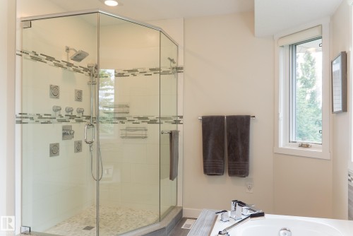 Glass-enclosed shower with multiple sprayers, a rainfall showerhead, and mosaic tile detailing - 56 Highridge Way, Stony Plain, AB - Indoor Photo Showing Bathroom
