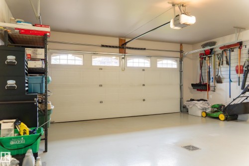 Garage with an overhead door featuring upper window panels, equipped with an automatic opener - 56 Highridge Way, Stony Plain, AB - Indoor Photo Showing Garage